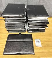 Stack of 20 black Amresoris faux leather folio tablet stands with one opened to show exterior and embossed logo