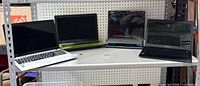Four laptops on shelf: silver Asus, green Asus, blue Gateway, black Asus