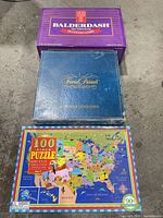 Three boxed items: Balderdash, Trivial Pursuit blue box, and 100-piece USA map puzzle