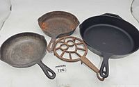 Three cast iron frying pans and trivet overview