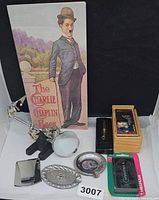 Group shot of all items including book, money clip, tool, ashtrays, lighter, card deck in box, key case