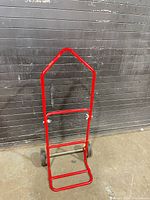 Front view of red collapsible hand truck showing frame, wheels, and folding toe plate