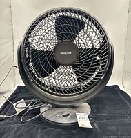 Front view of Honeywell tabletop fan showing grille, blades, base with control dial and power cord
