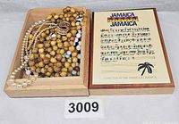 Contents displayed in open wooden box: faux pearls, brown wooden beads, black and white beads, ring