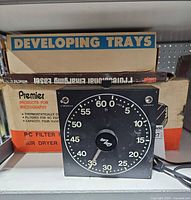 Front view of GraLab darkroom timer with boxed trays and air dryer behind