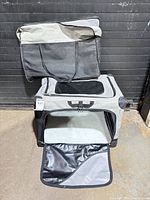 Carrier assembled with front flap open showing mesh windows and padded mat; storage bag displayed on top