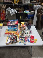 Overview of table with board games stack, bin of Playmobil parts and assorted small toys