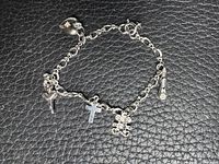 Full view of sterling silver charm bracelet showing heart tag, ballerina, cross, teddy bear, cylindrical charm and clasp