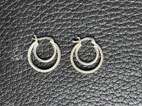 Pair of sterling silver hoop earrings on leather-textured background