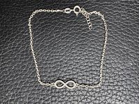 Full view of necklace laid flat showing infinity pendant, chain and extender