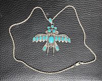 Front view of sterling silver thunderbird pendant with turquoise stones on rope chain