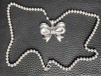 Pendant and portion of beaded chain displayed on black surface