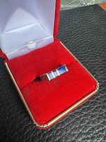 Ring in presentation box showing front view with blue stone inlays