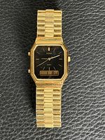 Front view showing gold-tone case, bracelet, black dial, LCD window
