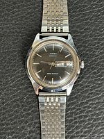 Front view of Timex watch showing dial, hands, indices, day-date window, bracelet.