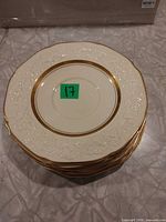 Stack of six ivory plates with gold rim and embossed border