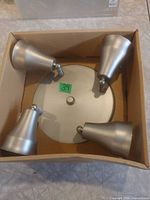 Top view of fixture in box showing base plate and four spotlight heads