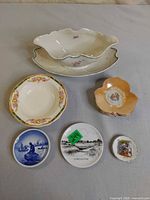 overview of all dishes including gravy boat, serving dish, floral plate, stack of peach dishes and three souvenir plates