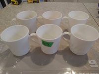 Six white CorningWare mugs grouped together