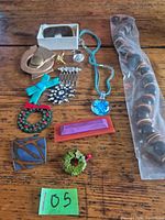 Overview of all jewelry items laid out on table including necklaces, brooches, rings, pins and bead necklace in sleeve