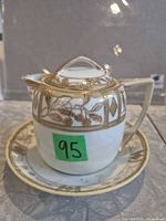 Jug with lid on matching underplate, gold hand painted motif visible