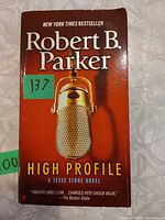 Front cover of High Profile paperback showing title, author, microphone artwork and bestseller tag