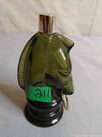 Front view of dark green horse head glass perfume bottle with silver cap and gold ring