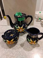 Front view of teapot, sugar bowl and creamer showing patterns