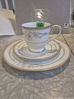 Cup on saucer atop dinner plate showing pattern and gold trim