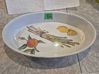 Top view of oval porcelain dish showing fruit and vegetable decoration