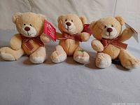 Three tan Russ Brady miniature teddy bears with tags and ribbons