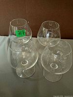 Four clear glass snifter glasses arranged upright showing overall shape and clarity