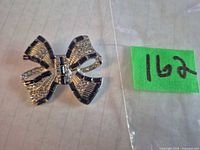 Front view of silvertone bow brooch showing rhinestones and enamel detail