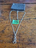 Necklace laid out showing chain, extender and heart pendant with lot number