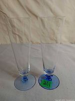 Two tall clear beer glasses with blue feet front view