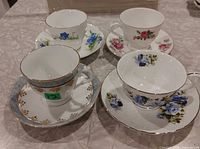 Four teacup and saucer sets arranged on table