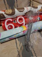 Multiple wrapping paper rolls, numeral candles 6 and 9, bundle of sparklers on fabric surface