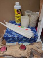 Lot overview showing taper candles, flameless pillars, pillar candle, fondue fuel, driftwood holder, tealights, decorative box