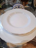 stack of white dinner and salad plates on glass table