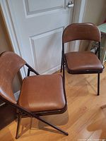 two brown vinyl padded folding chairs