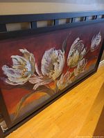 Front view of framed canvas showing floral subject and black frame