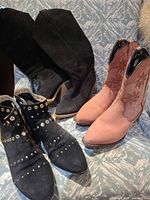 Three pairs of boots on chair: black suede knee-high, black studded ankle, apricot mid-calf