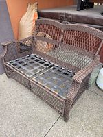Brown resin wicker loveseat frame showing overall structure and condition