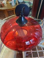 Side view of red glass pendant light showing shade, canopy and cord