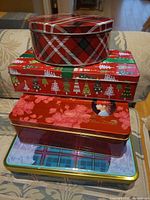 Stack of four assorted metal cookie tins showing patterns and sizes