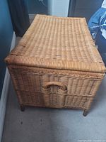 Closed woven rattan chest showing exterior weave, lid and side handle