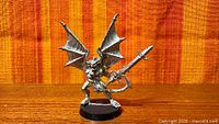 Front view of unpainted metal Chaos Daemon with wings and sword on round base