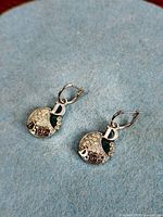 Close-up of both earrings displaying logo, crystals, and lever-backs