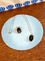 ring and pendant on blue pad showing design and chain