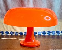 Front view of orange mushroom table lamp lit